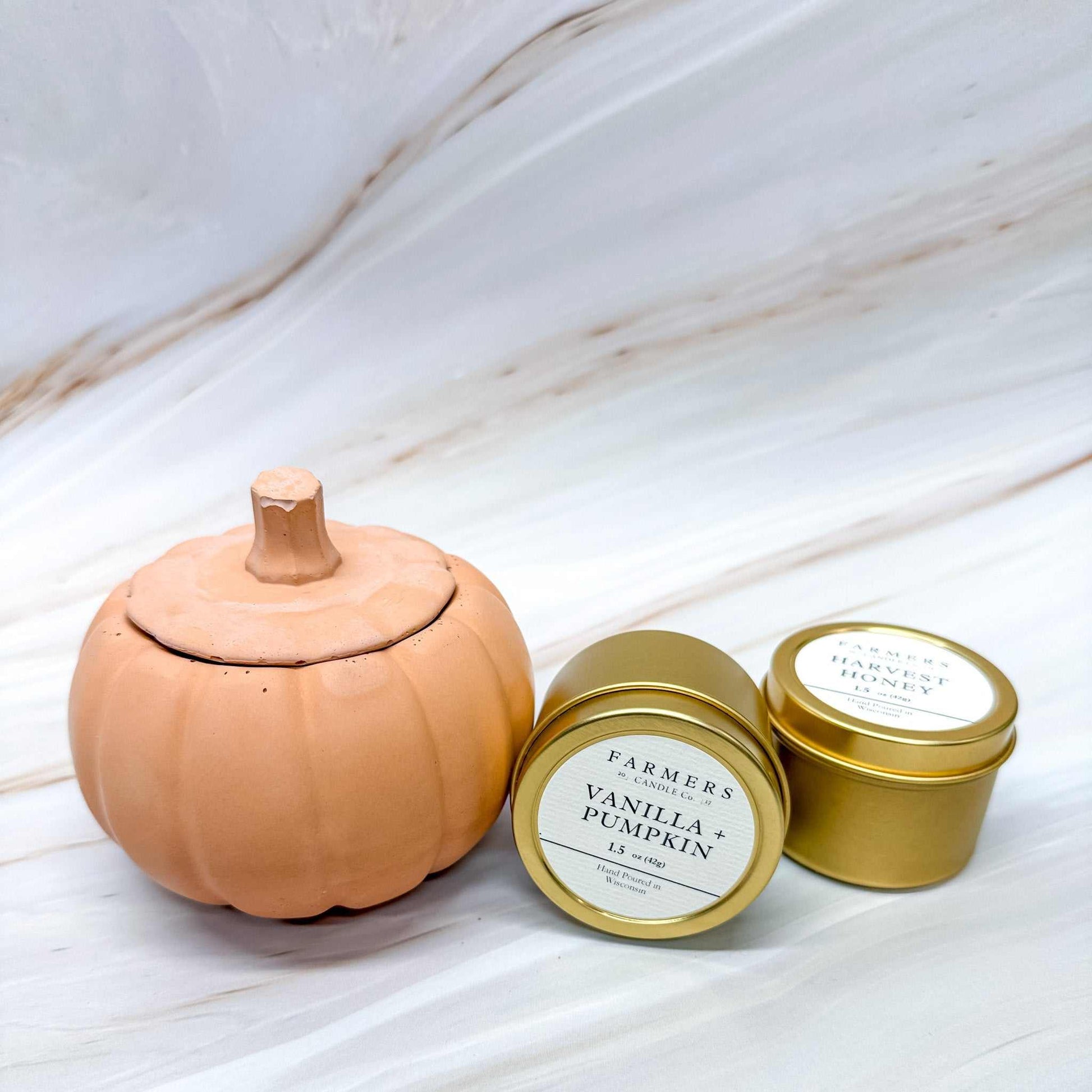 Modern concrete pumpkin tealight holder with golden tin candle, available in black, terra cotta, and gray